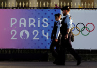 FILE PHOTO: French gendarmes patrol a street near a poster advertising the Paris 2024 Summer Games in Paris