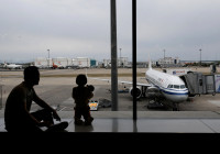 FILE PHOTO: Passengers look at the tarmac as they wait for their flights at the Beijing Capital International Airport, in Beijing